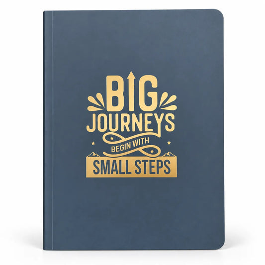 A navy blue hardcover notebook with a gold foil-style graphic on the front that reads 'BIG JOURNEYS BEGIN WITH SMALL STEPS' on a clean white background.