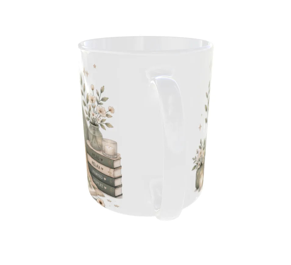 A white ceramic mug featuring a delicate vintage-style illustration of stacked books, a candle, and floral arrangements in vases.