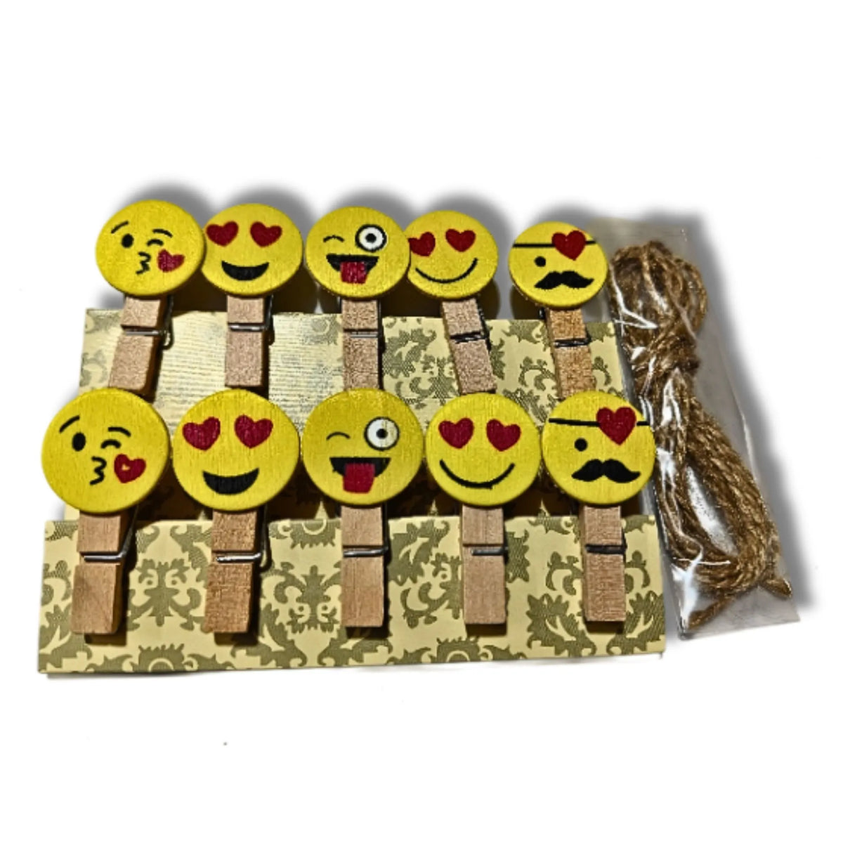 A set of nine yellow emoji-themed wooden clothespins with red heart and black facial details, displayed on a patterned backing card next to a bundle of twine on a white background.