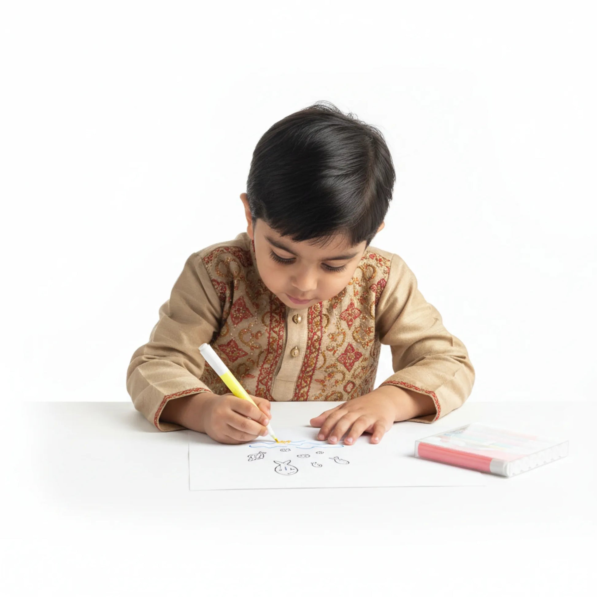 Child in traditional attire coloring on a white sheet of paper with markers.