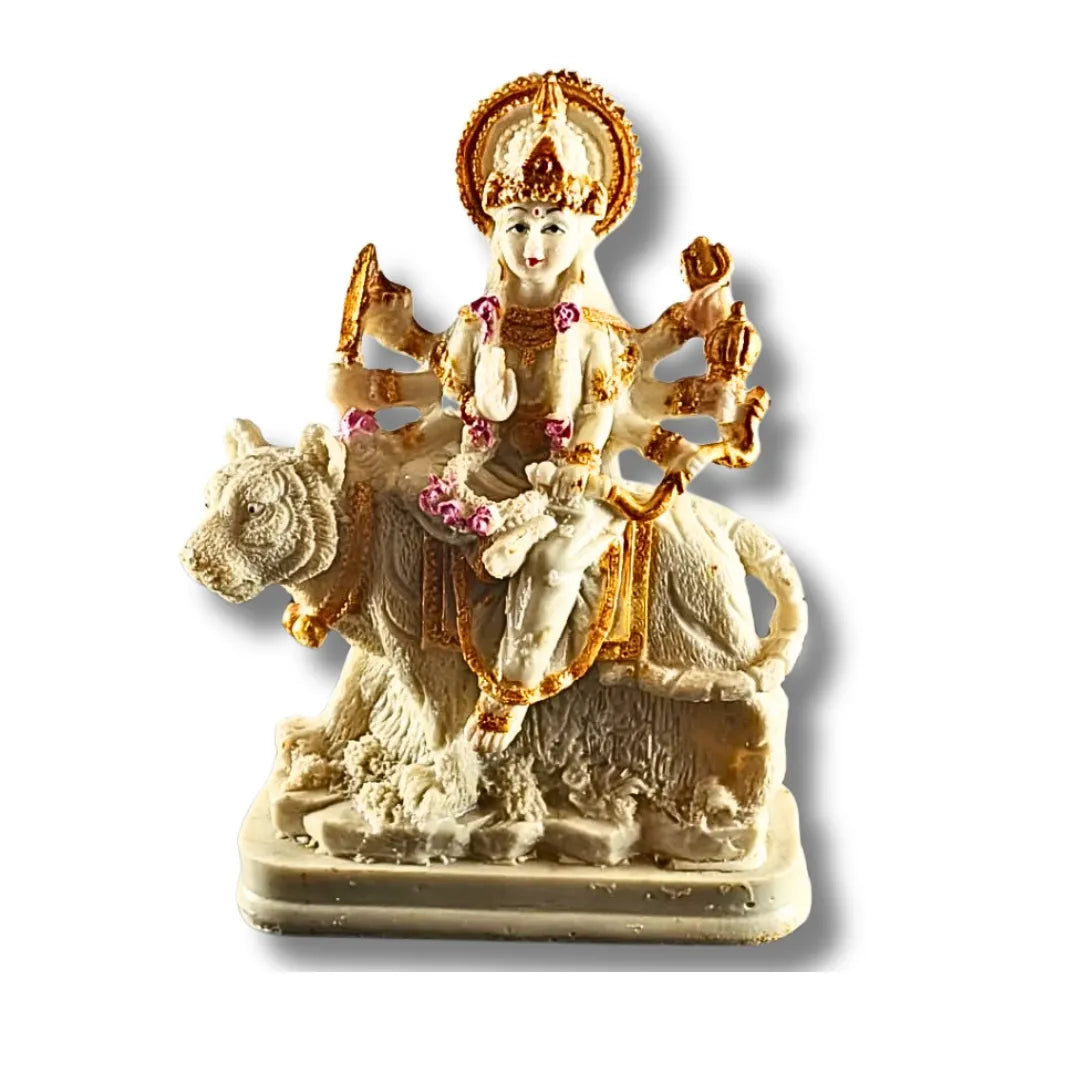 A small decorative statue of a seated female deity on a camel, shown against a plain white background with a soft drop shadow. The figure is primarily off-white/ivory with prominent gold detailing and small pink floral accents.
