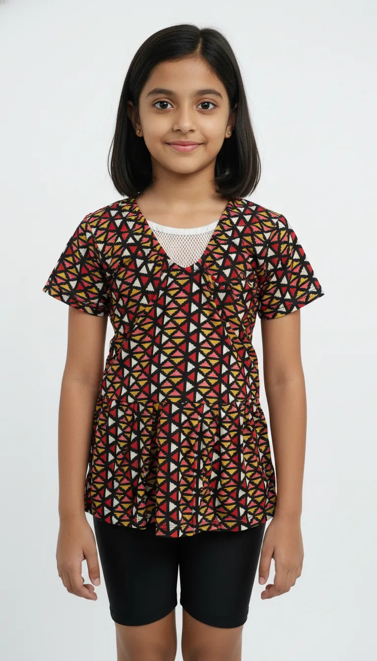 Young girl wearing a patterned top and black shorts on a white background