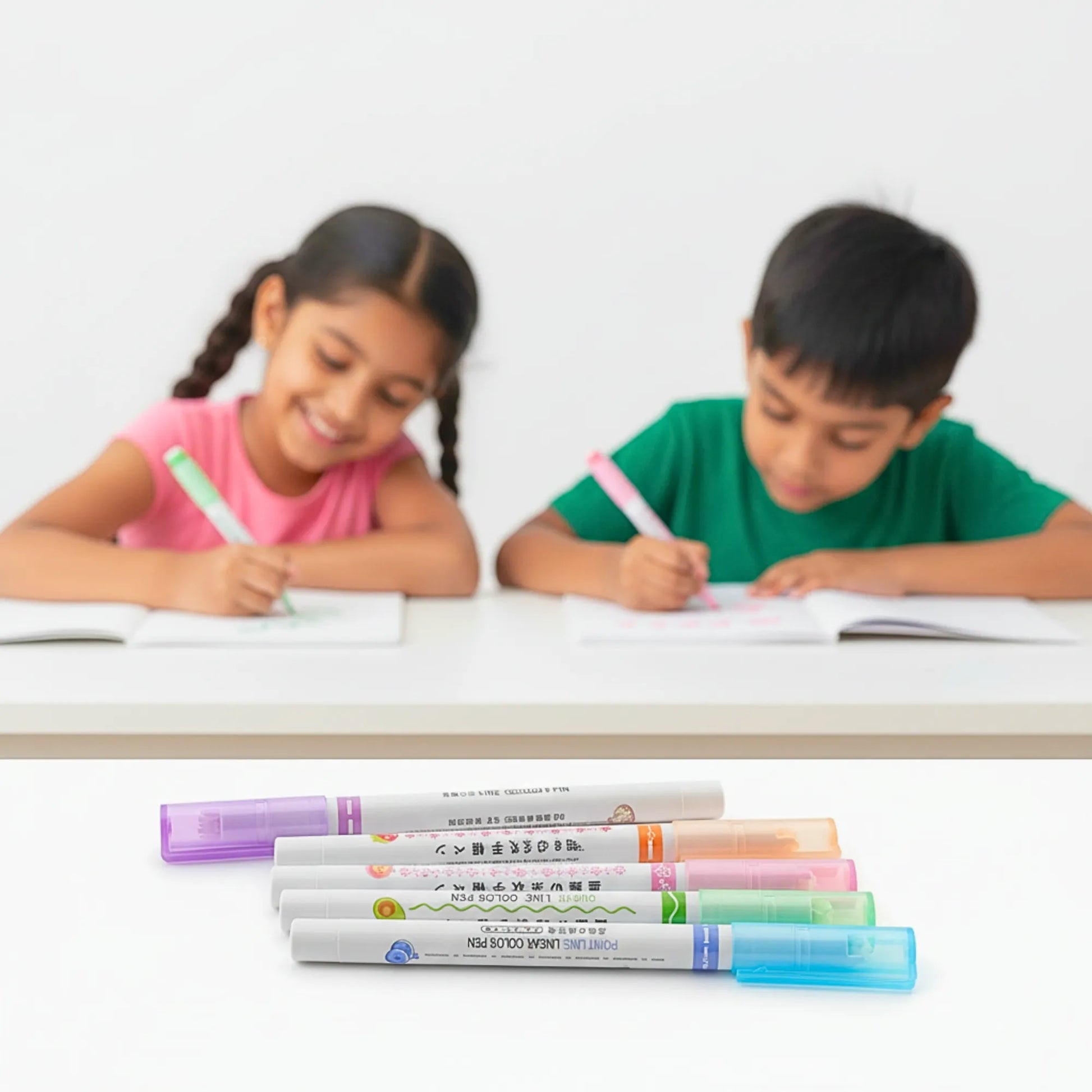 Two children sitting at a table with writing materials, including colorful markers.