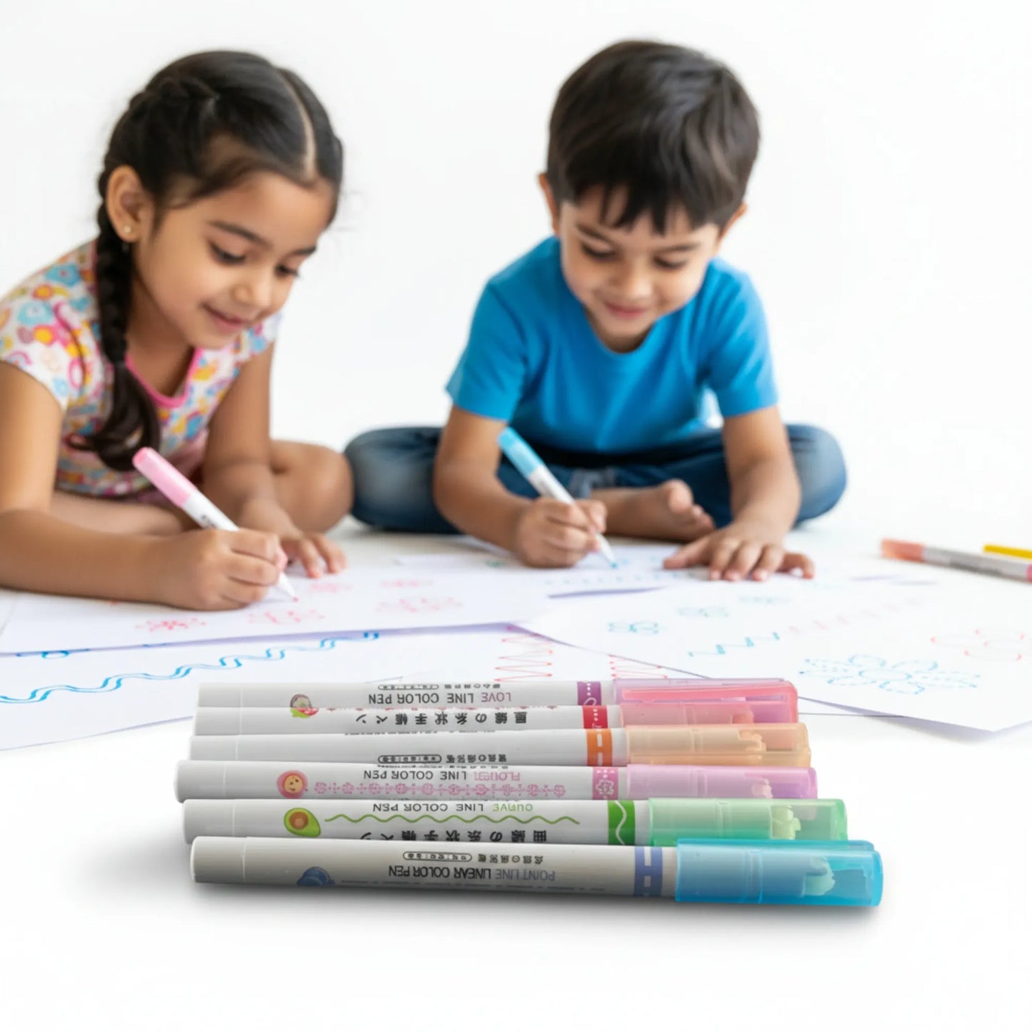 Two children sitting on the floor with markers and paper, surrounded by markers on a white background