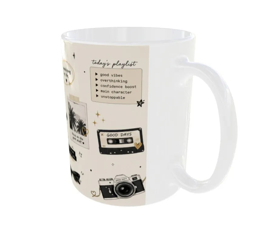 A white ceramic mug with a cream-colored wraparound print featuring retro cassette tapes, cameras, stars, and a 'today's playlist' list.