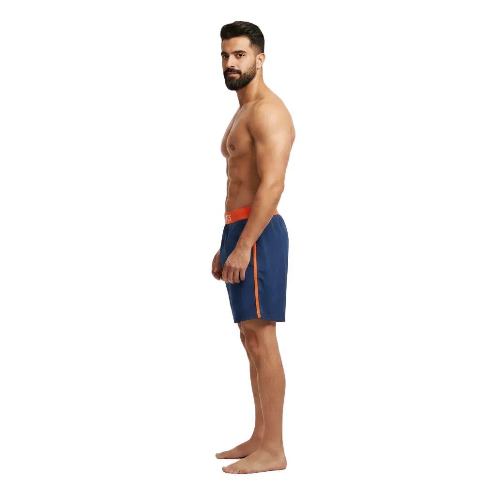 Man wearing blue swim shorts with orange accents on a white background