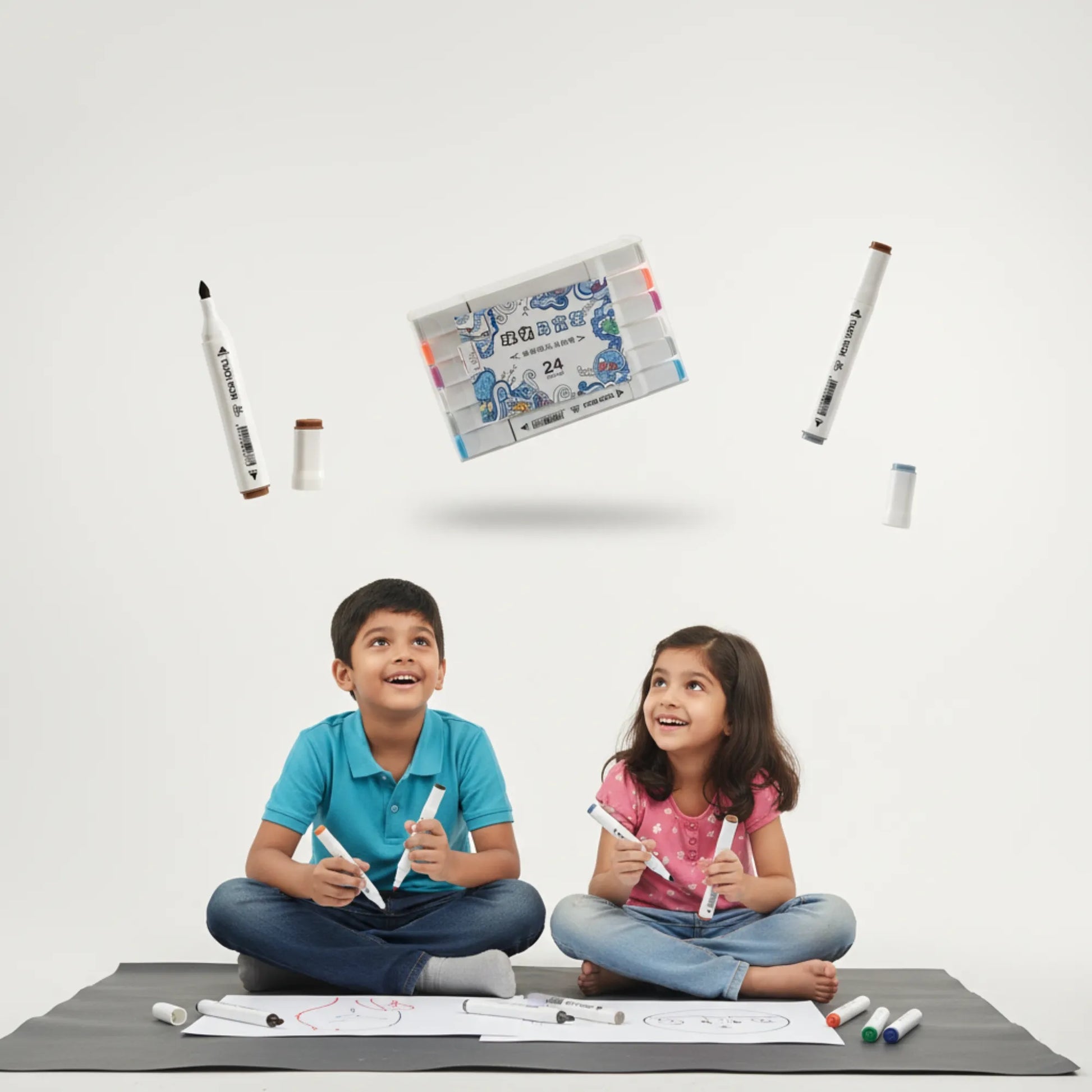 Two children sitting on the floor with markers and paper, surrounded by stationery items on a white background.