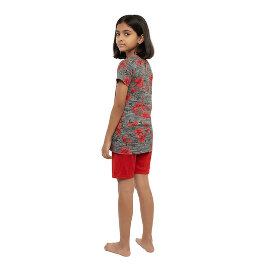 Young girl wearing a patterned shirt and red shorts on a white background