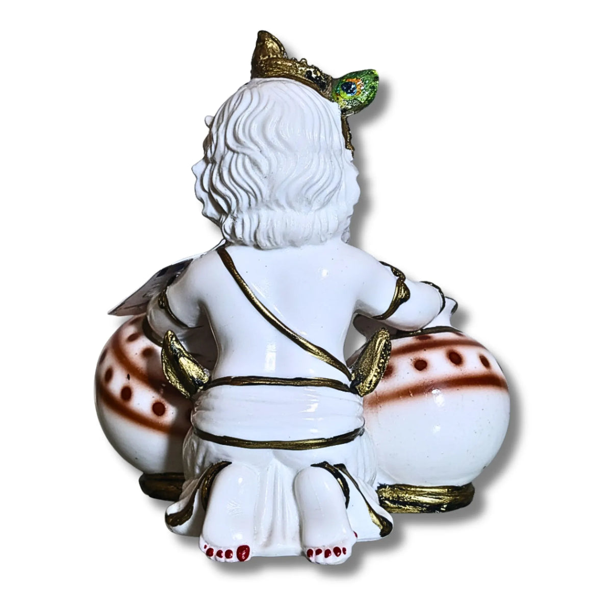 A white porcelain figurine of a seated figure with curly hair, gold trim, and red accents, shown from the back against a plain white background.
