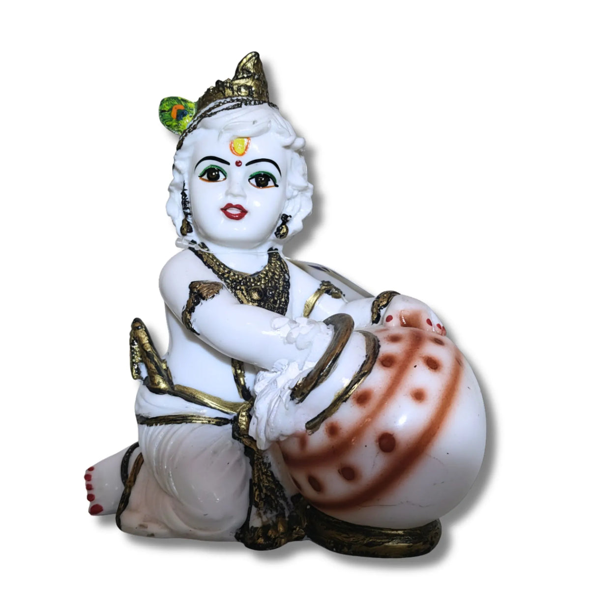 A white porcelain figurine of a child deity playing a decorated drum, featuring gold accents, red painted details, and a green and gold crown, set against a plain white background.