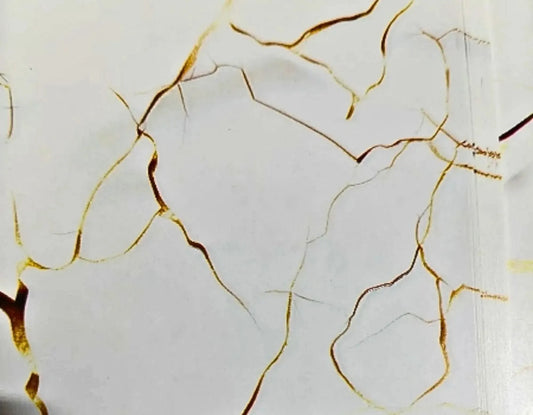 White marble-look surface with irregular metallic gold veining and a few darker brownish-gold marks.