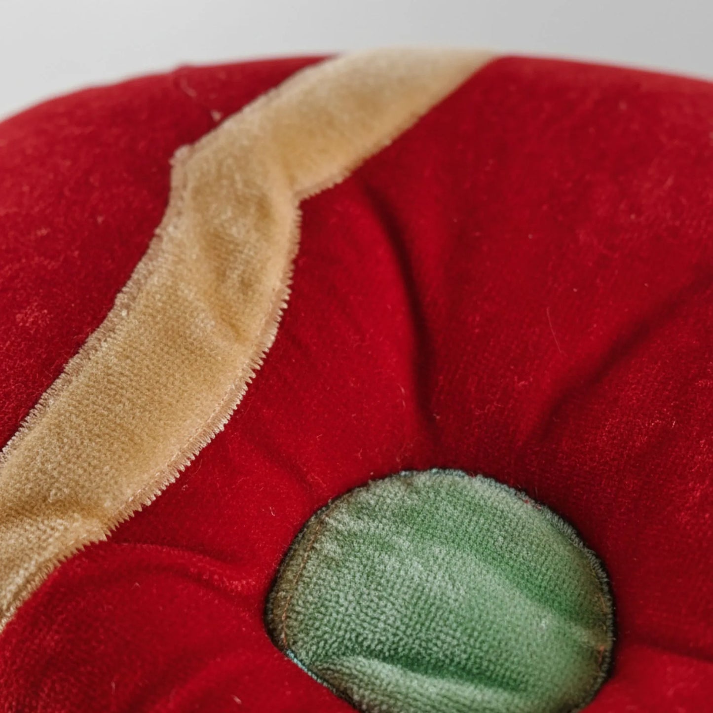 Close-up of a red fabric with a green button and beige border.