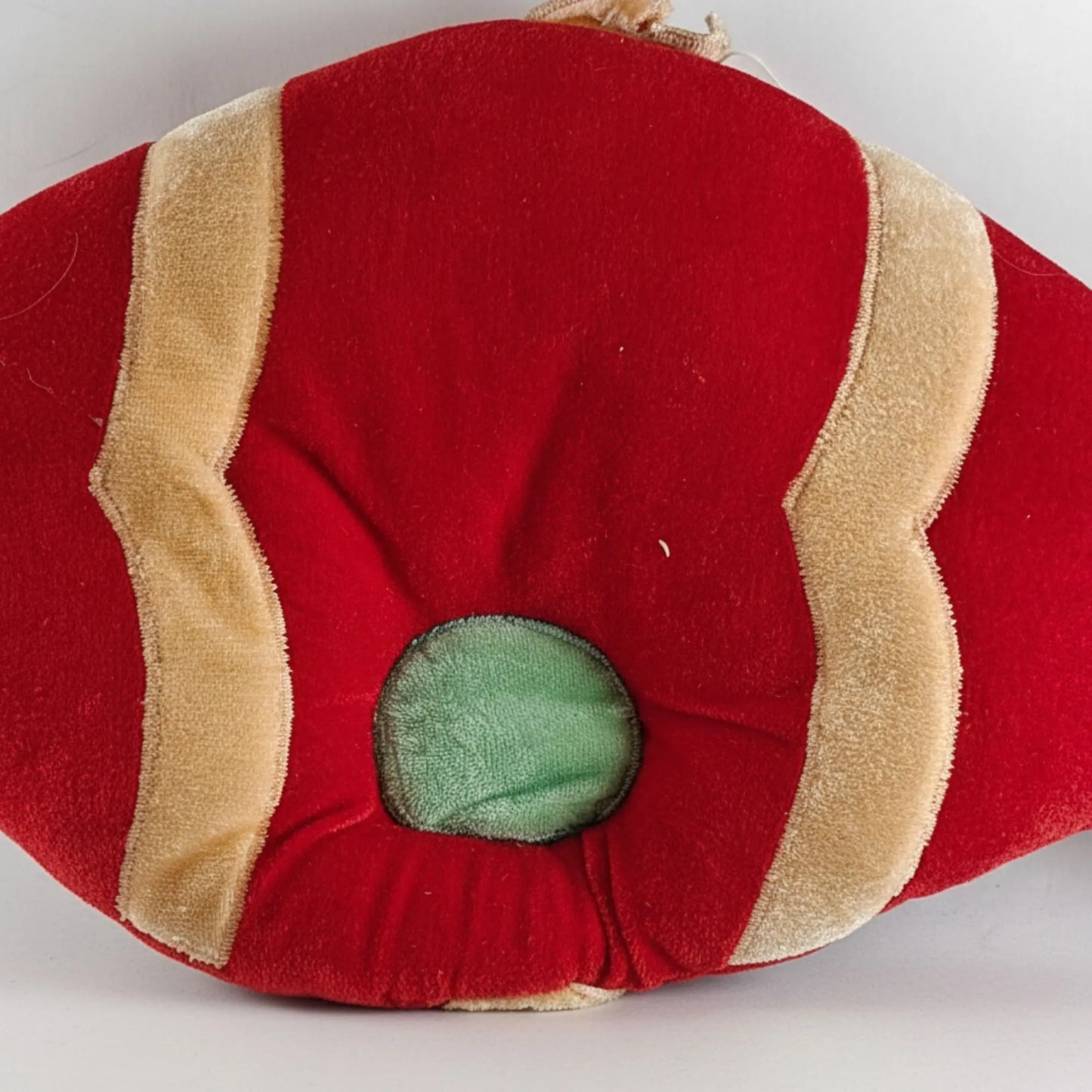 Red and beige fabric item with a green center on a white background