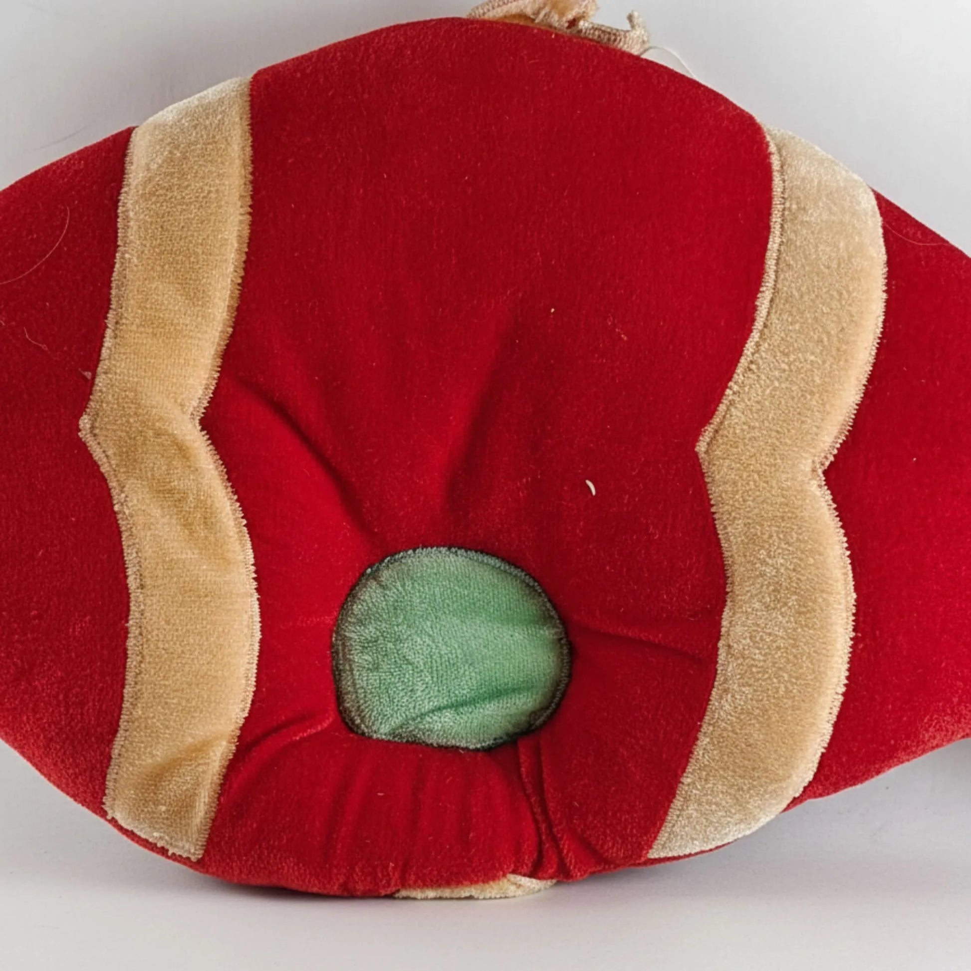 Red and beige fabric item with a green center on a white background