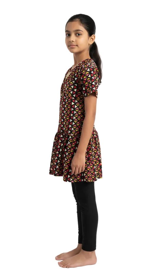 Girl wearing a patterned brown dress with black pants on a white background