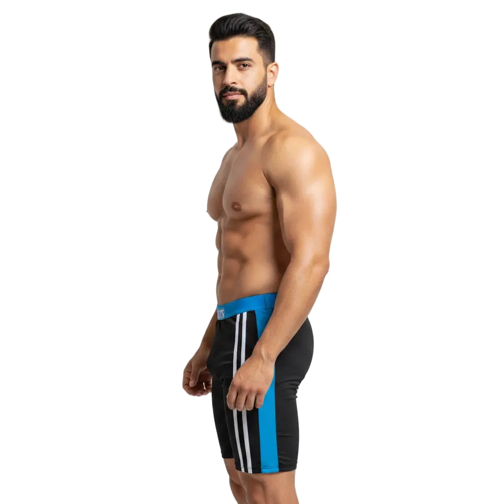 Man wearing black swim trunks with blue and white stripes on a light gray background